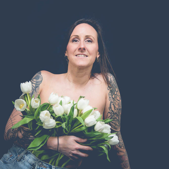 Portraitiste - Portrait d'une femme tatouée en jean portant une brassière de tulipes blanches en guide de bustier